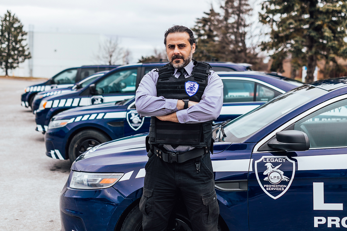 Legacy patrol guard standing near security patrol vehicle